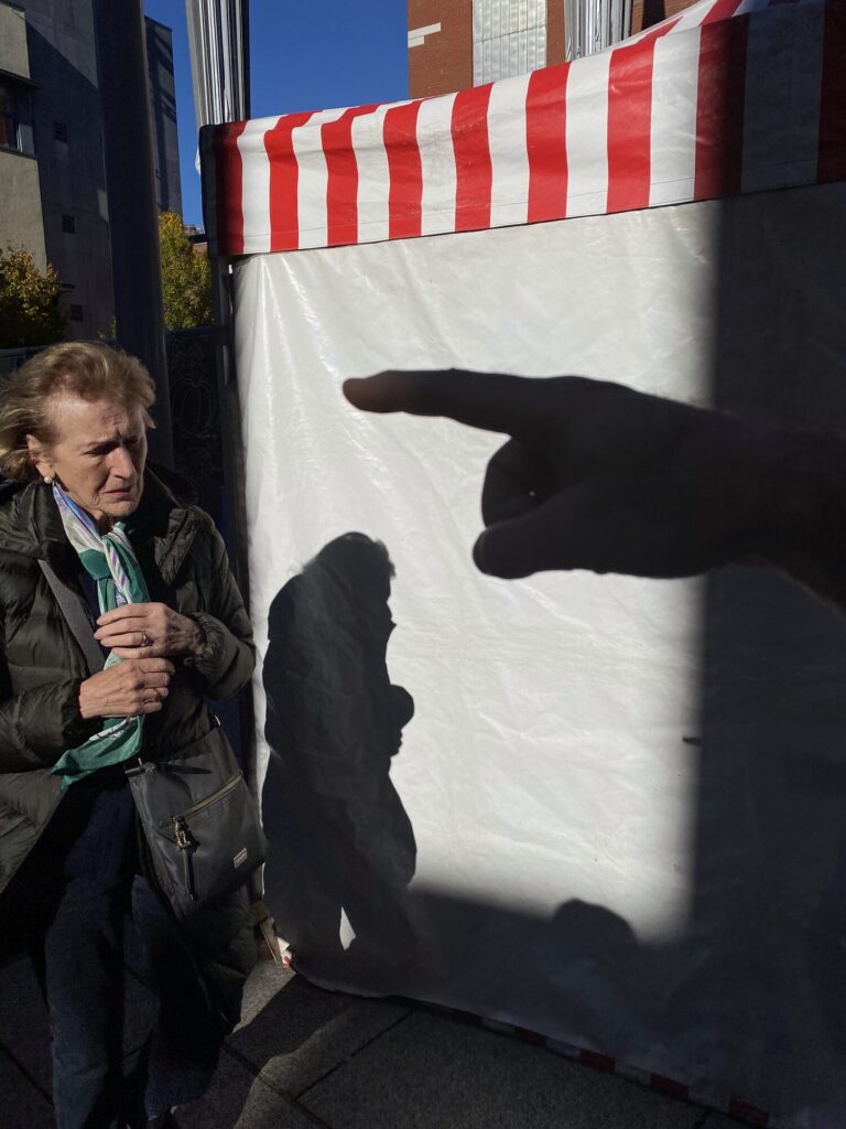 Street photograph of a pointing shadow falling on a striped awning beside a woman in Dublin taken on a Brendan Ó Sé street photography workshop